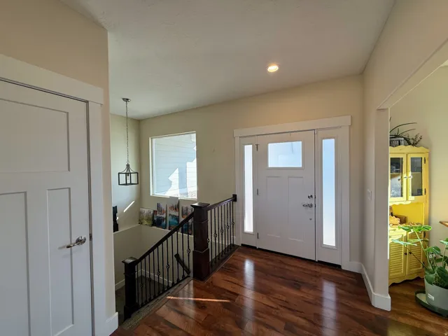 Entryway featuring a solid wood door with glass inserts, two sidelight windows, rich wood-finish flooring, and a contemporary ceiling light fixture