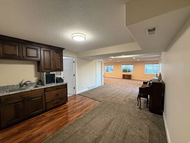 Kitchenette with dark wood cabinetry, granite-style countertop, and stainless steel sink