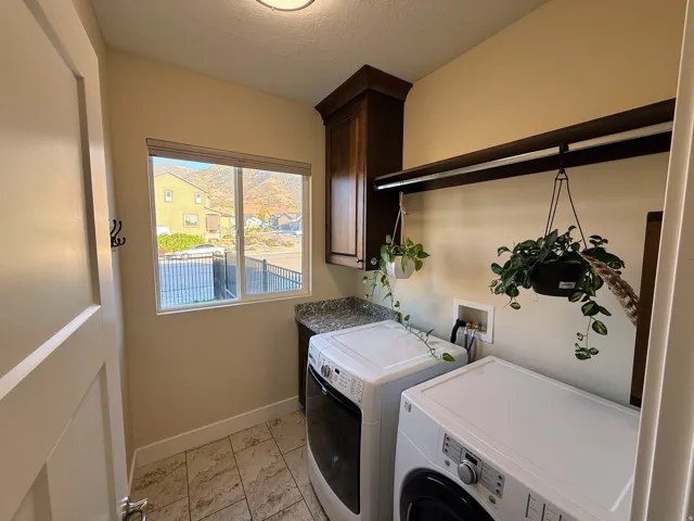 Laundry area featuring a window, tile flooring, built-in cabinetry, counter space, and a hanging clothes rod