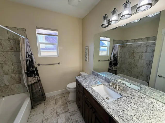 Bathroom featuring a single vanity with stone countertop, integrated sink, and an expansive mirror