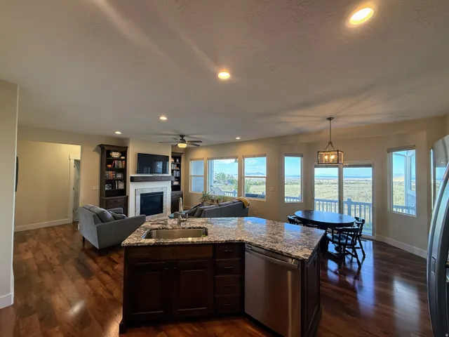 Open-concept living area with dark wood-finish flooring, a built-in fireplace with a stone surround, and integrated shelving units