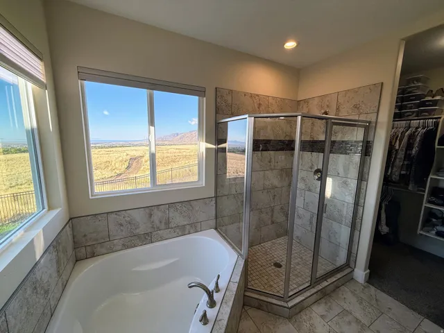 Soaking tub with a tiled surround, adjacent to a glass-enclosed shower with tile walls and a tiled floor