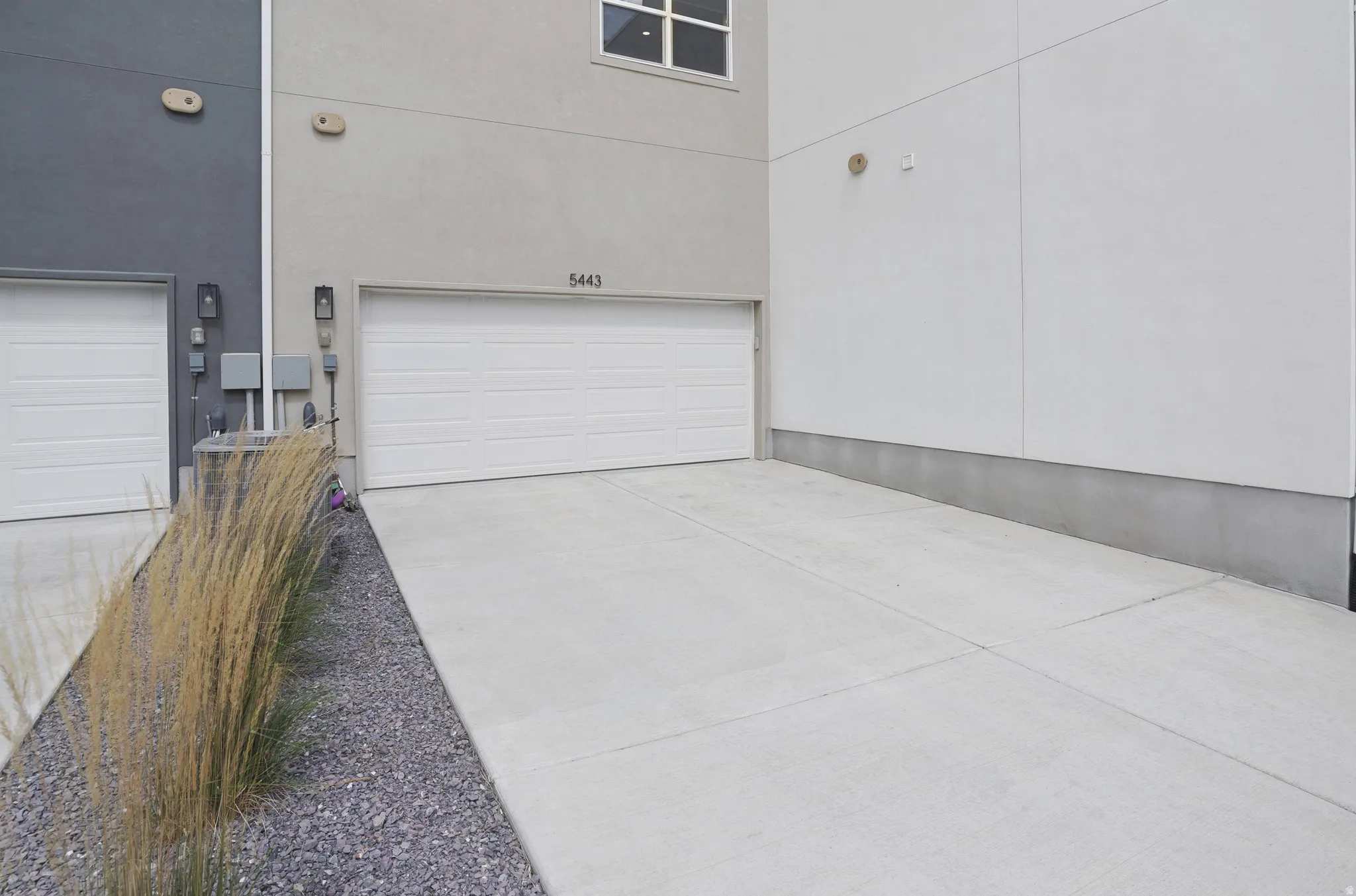 Concrete driveway with a single garage door and exterior wall sconces