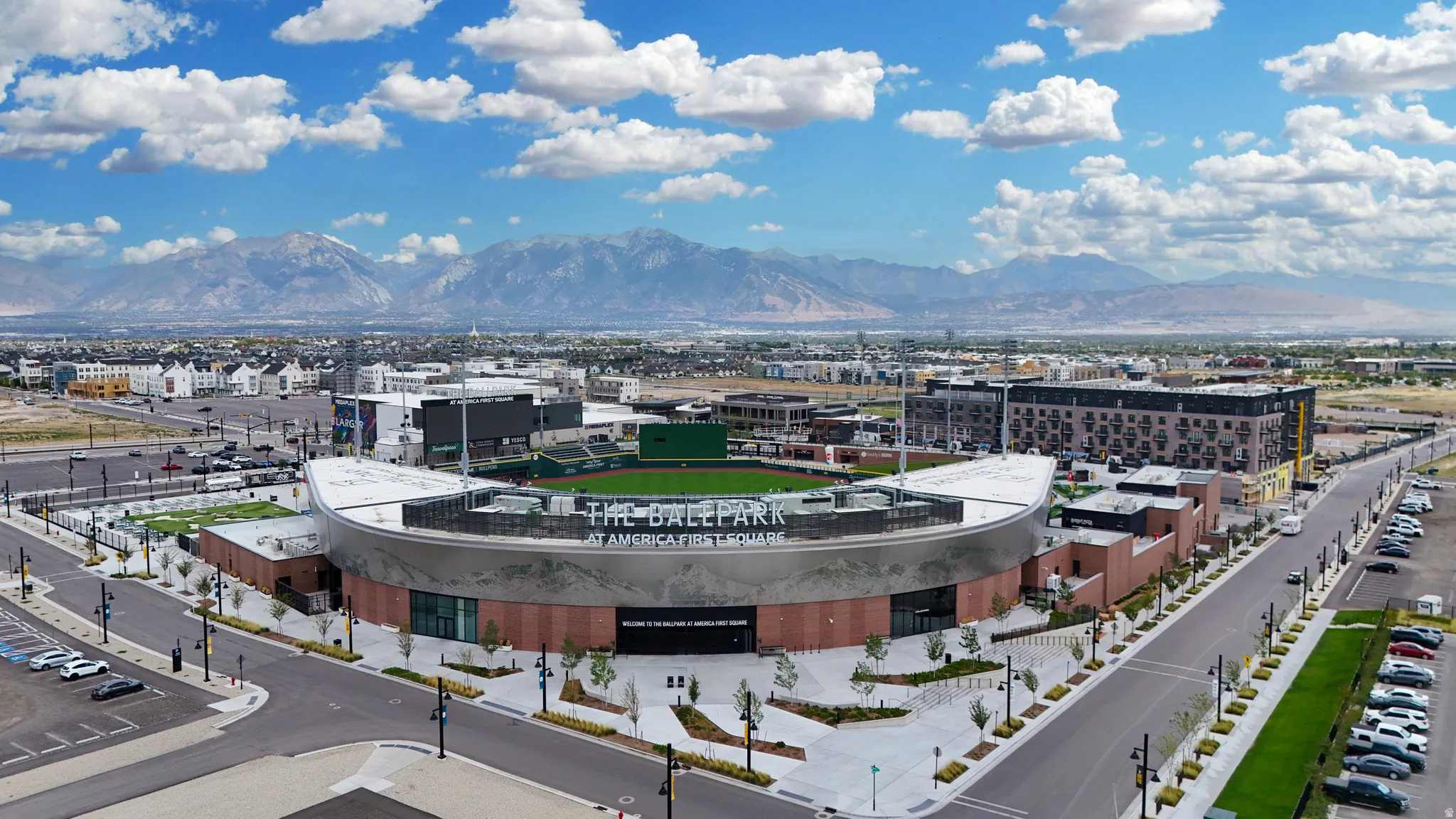 Stadium with a curved façade, surrounded by paved roads and structured landscaping