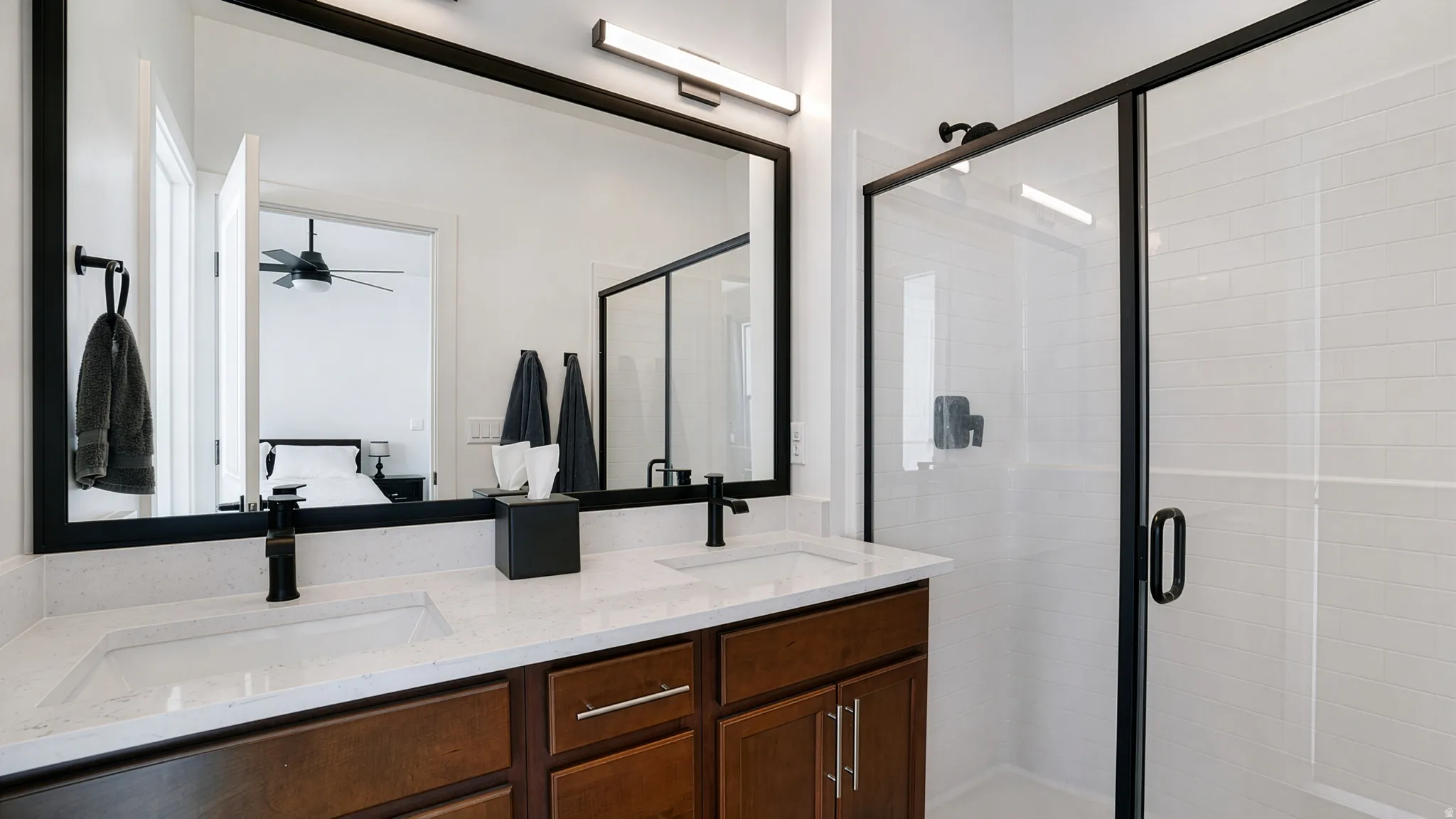 Dual vanity with integrated sinks, dark wood-finish cabinetry, and matte black hardware