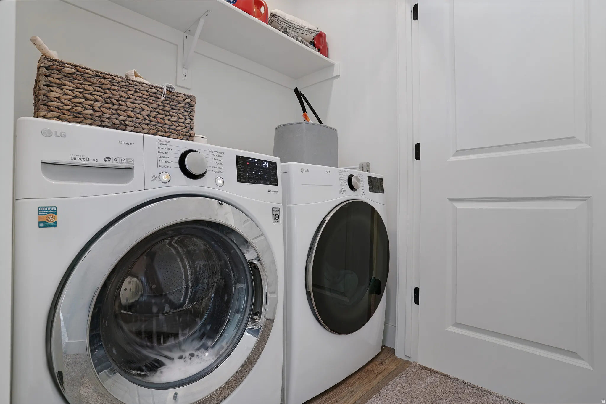 White shaker-style doors with black hardware, wood-finish flooring, and wall-mounted shelving