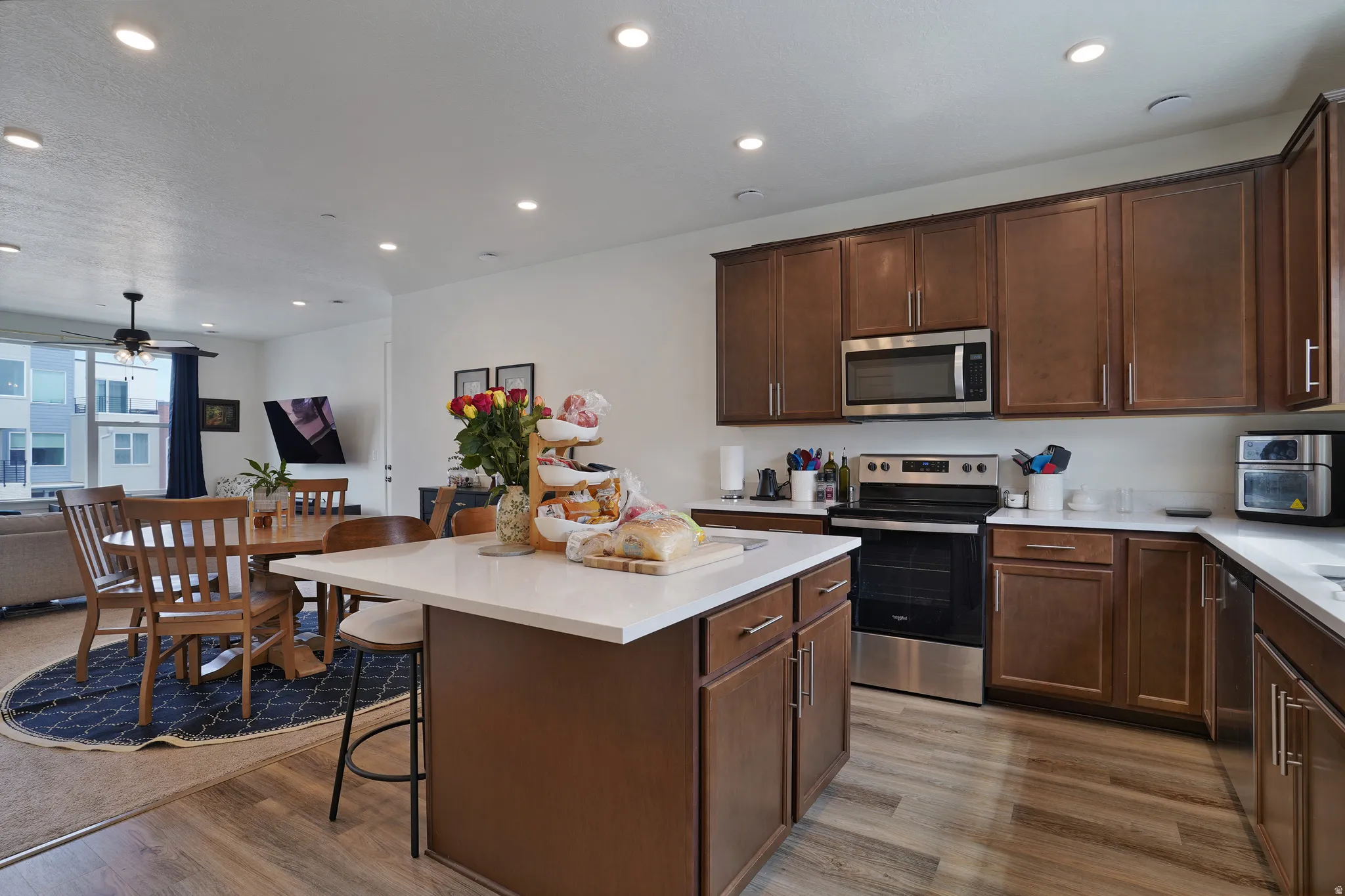 Kitchen featuring wood-finish flooring, white countertops, dark wood-finish cabinetry, and stainless steel appliances