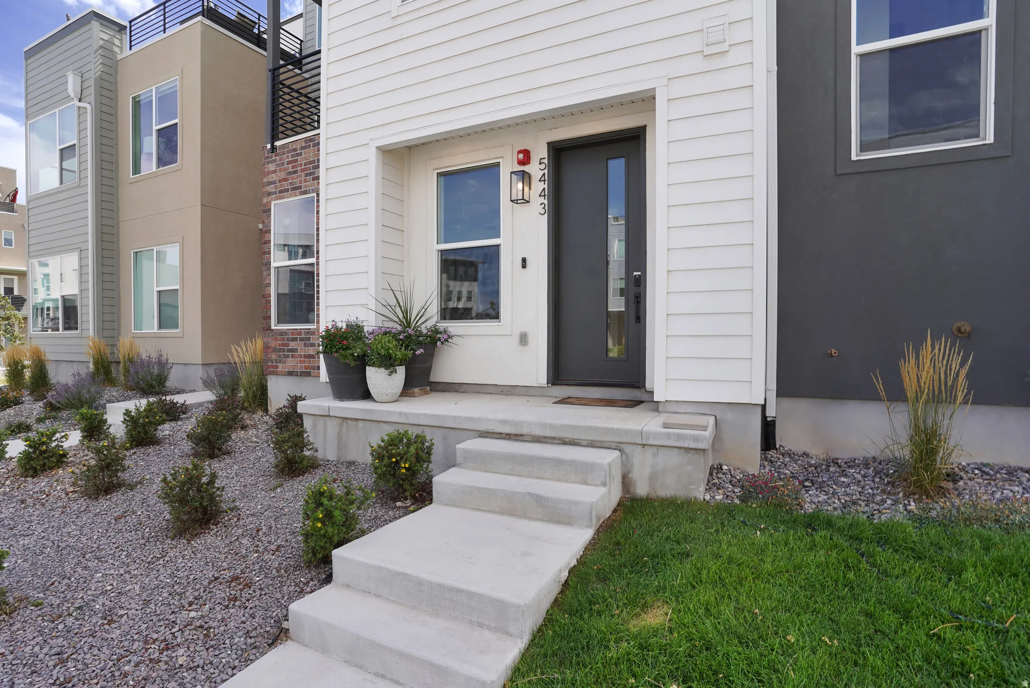 White horizontal siding exterior with a dark-framed entry door featuring a vertical glass insert