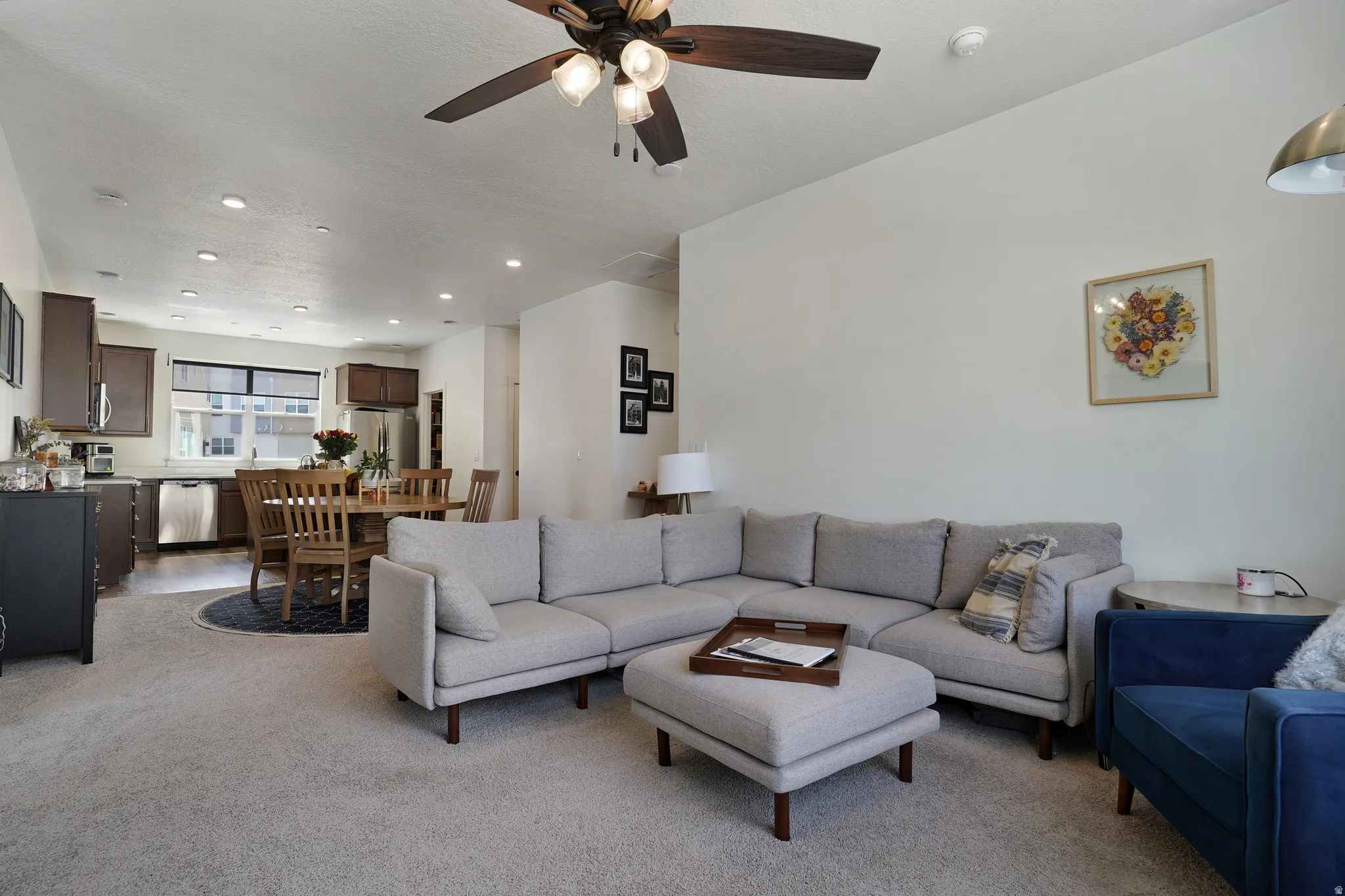 Open-concept living space with a ceiling fan, recessed lighting, and light-toned carpeting