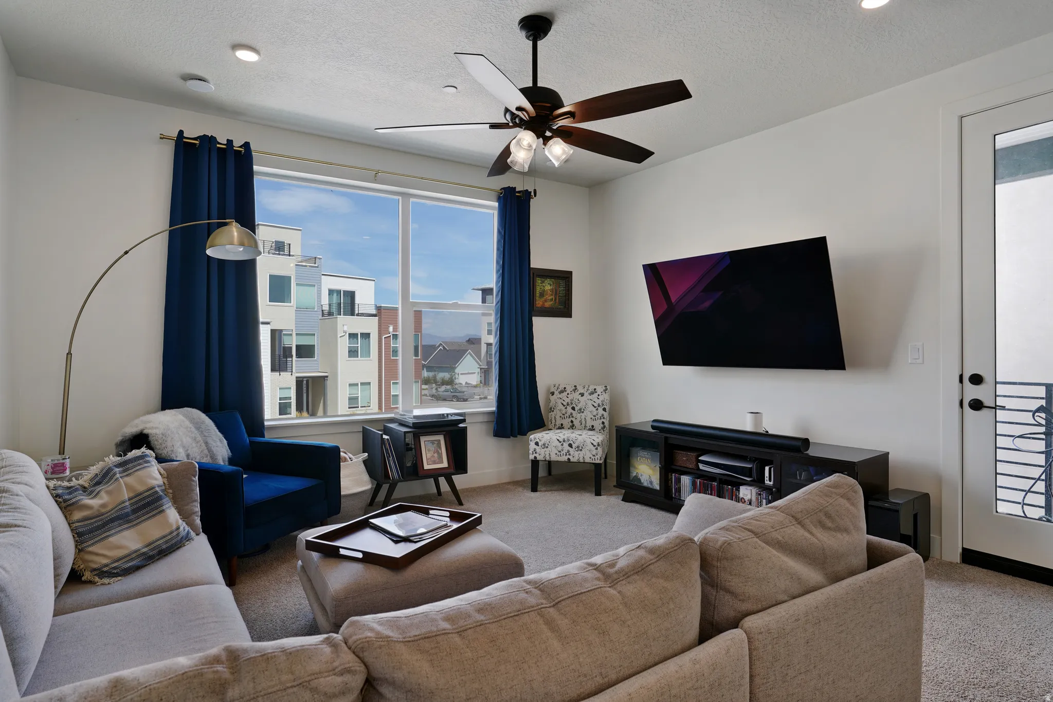 Living area featuring a ceiling fan, recessed lighting, expansive window, mounted television, and a built-in media console