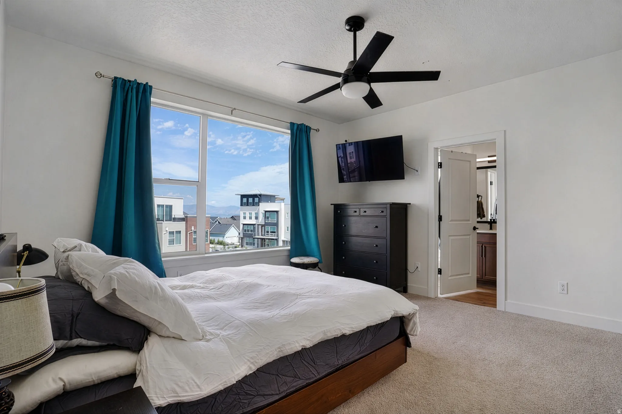 Light-toned carpeting, white walls, and a black ceiling fan with an integrated light fixture