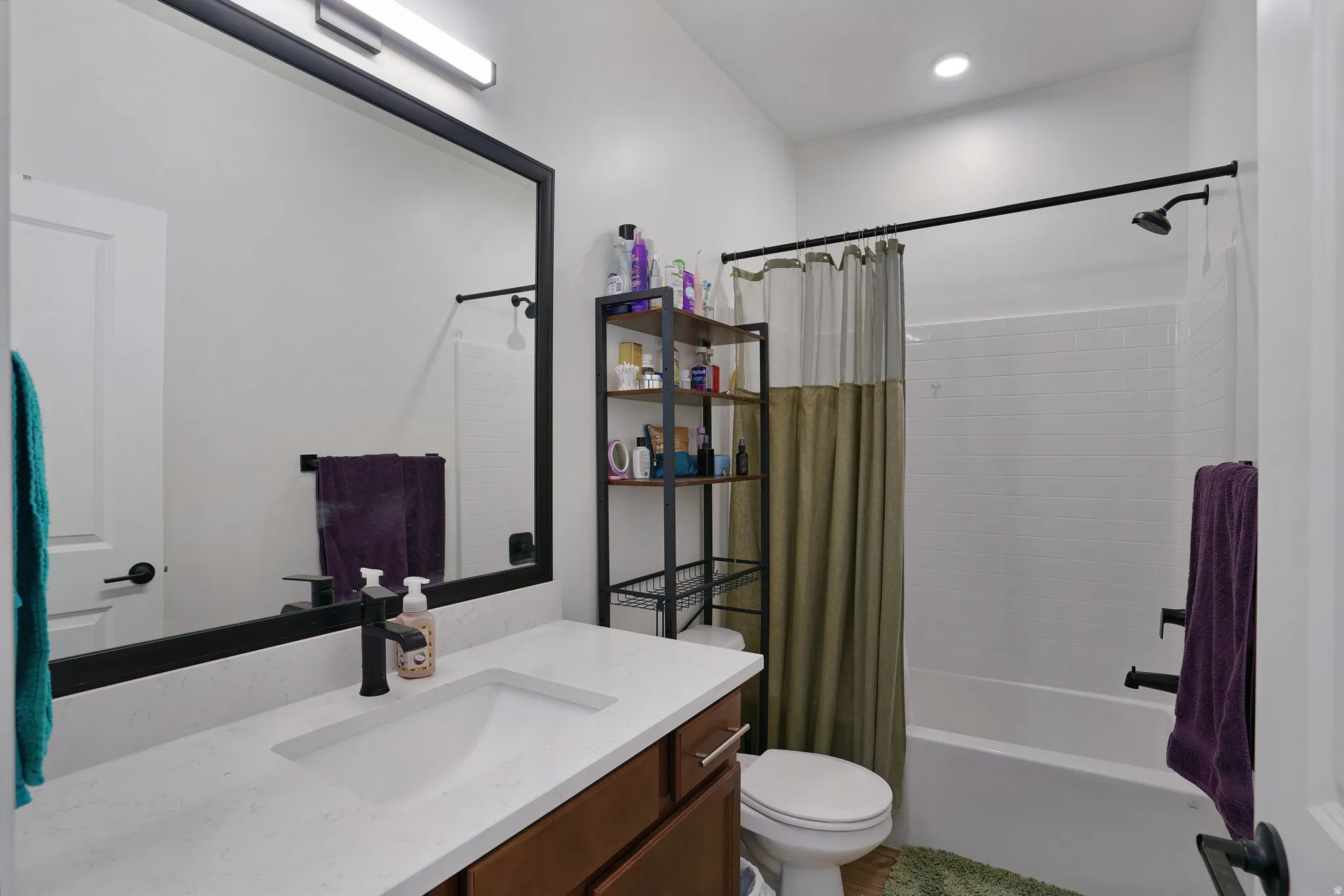 Bathroom featuring a vanity with a white countertop and undermount sink, matte black faucet, framed mirror, and a tub-shower combination with white subway tile
