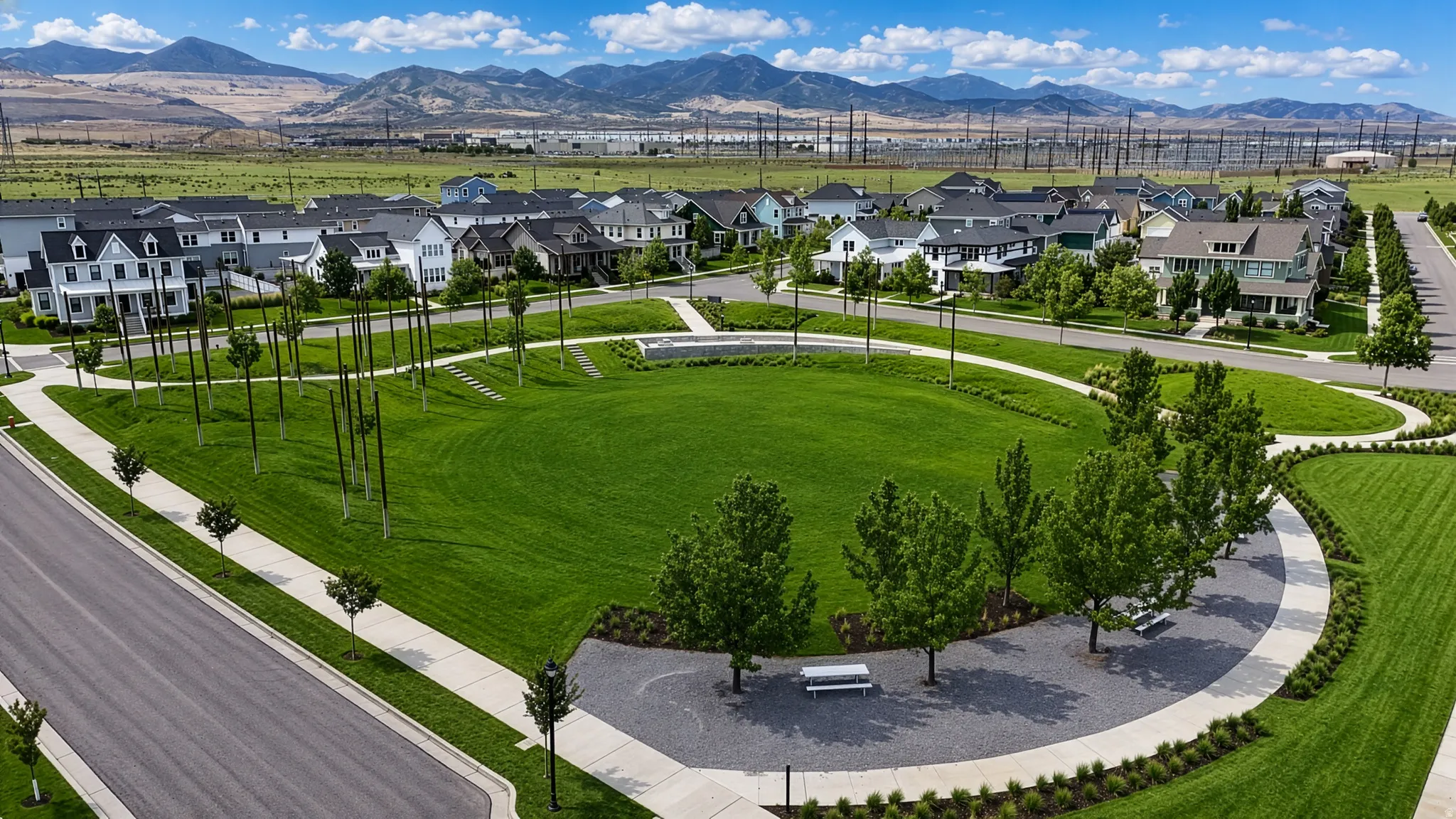 Expansive green space featuring a walking path, mature trees, and community seating