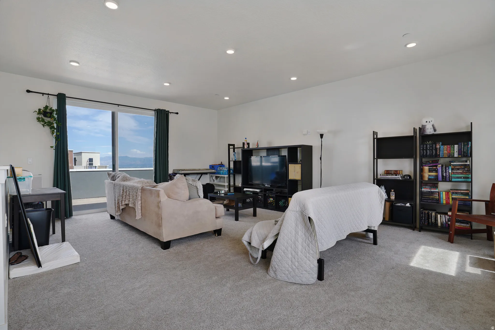 Recessed lighting illuminates this open living space featuring light gray carpeting and white walls