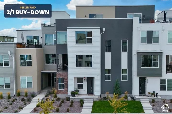 Contemporary multi-level townhome exterior featuring a mix of horizontal siding, stucco, and brick veneer, large windows, and private rooftop terrace space