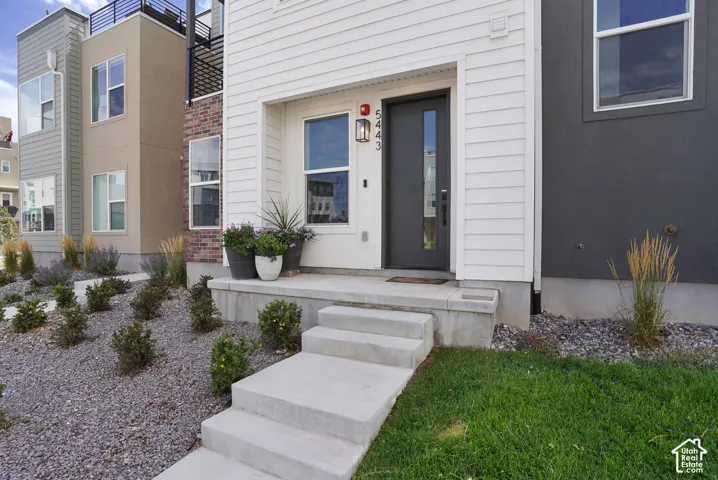 White horizontal siding exterior with a dark-framed entry door featuring a vertical glass insert
