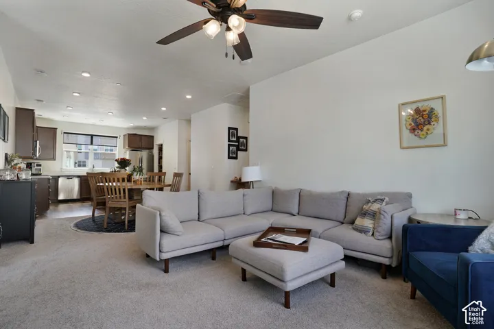 Open-concept living space with a ceiling fan, recessed lighting, and light-toned carpeting