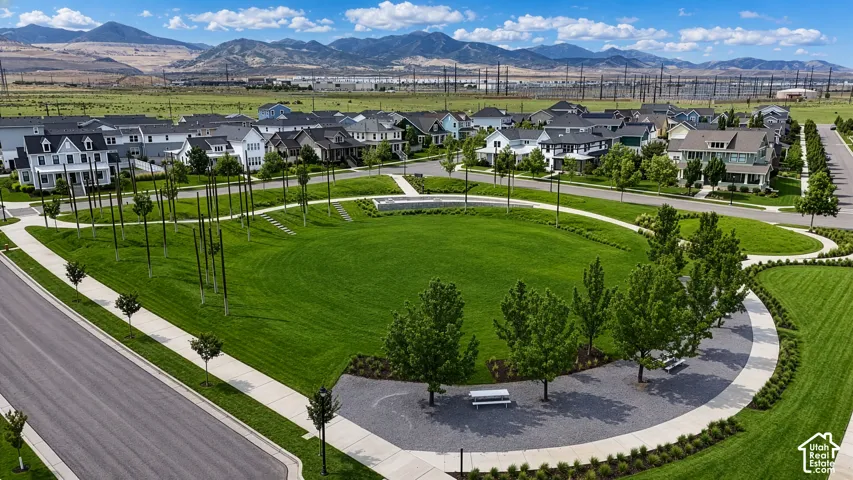 Expansive green space featuring a walking path, mature trees, and community seating