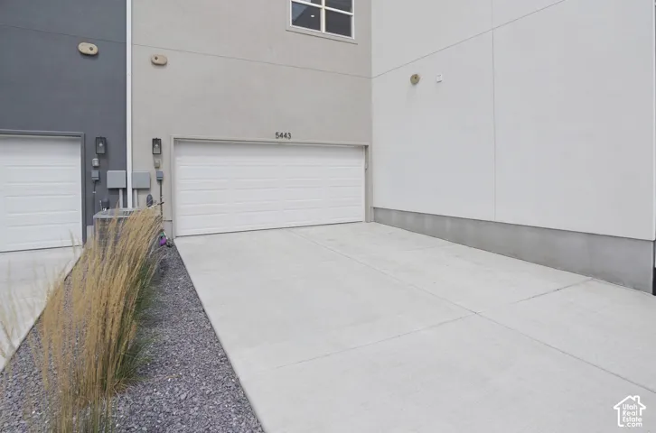 Concrete driveway with a single garage door and exterior wall sconces