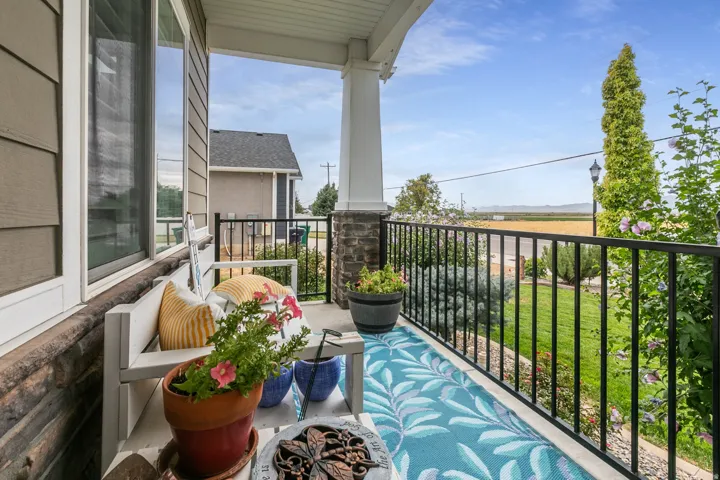 Covered front porch featuring a stone column base and black metal railing