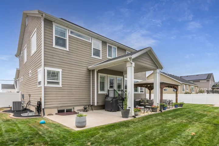 Expansive backyard featuring a manicured lawn, a covered patio, and an additional outdoor pergola