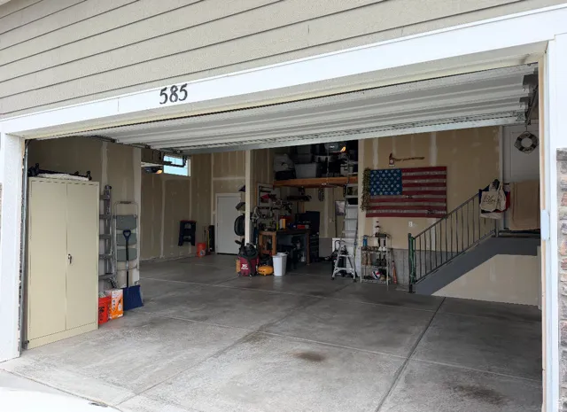 Spacious garage with concrete flooring, a side entry door, and interior stair access