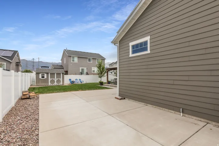 Side yard with concrete patio, gravel border, and privacy fence