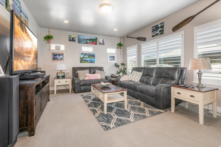 Recessed ceiling lighting, light-toned carpeting, transom windows, window shutters, and a built-in media console