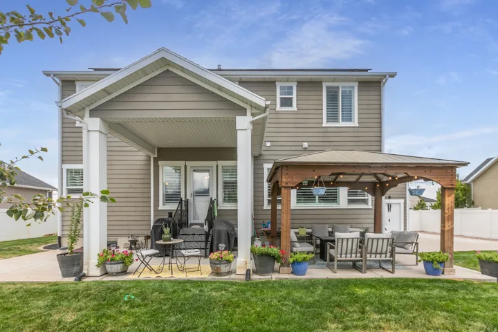 Expansive lawn with a concrete patio, covered porch, and a wood-frame gazebo