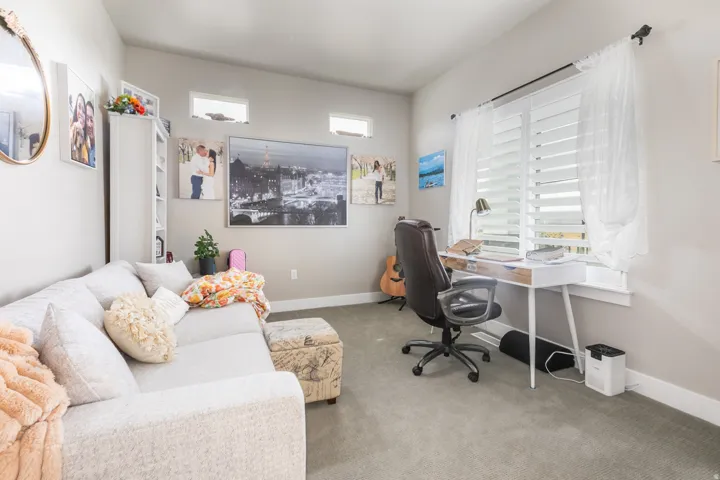 Carpeted room with a large window featuring white plantation shutters
