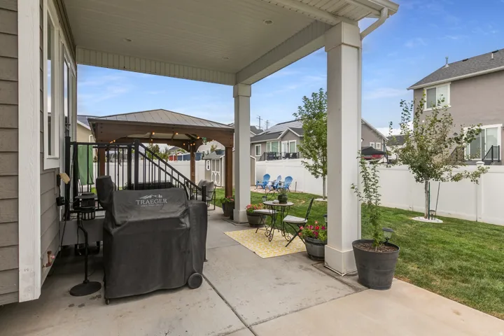 Covered patio with concrete flooring, white support columns, and a railing system