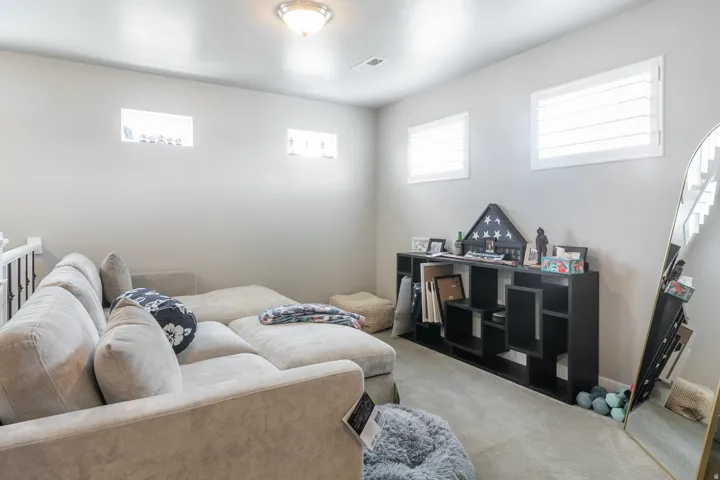 Carpeted interior space with flush-mount lighting, two upper transom windows, and two windows with white plantation shutters