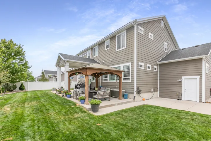 Expansive backyard featuring a manicured lawn, a covered patio, and a dedicated concrete pad