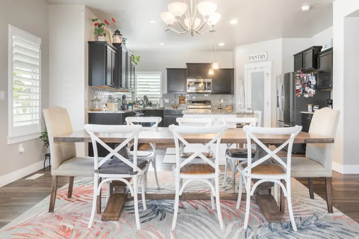 Wood-finish flooring, plantation shutters, dark cabinetry, stainless steel appliances, and a pantry with a frosted glass door