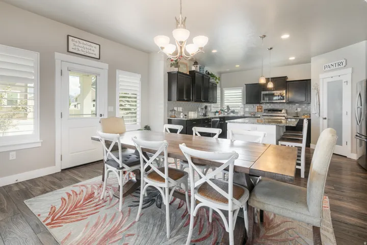 Open-concept living area featuring wood-finish flooring, a kitchen island with seating, dark cabinetry, and recessed lighting