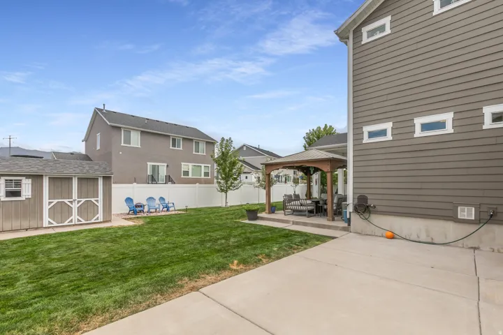 Expansive backyard featuring a lush lawn, concrete patio, and a dedicated storage shed