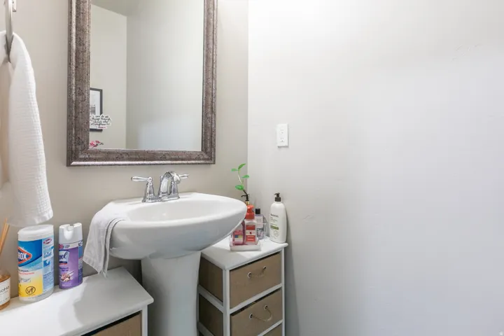Pedestal sink with chrome fixtures and an ornate framed mirror