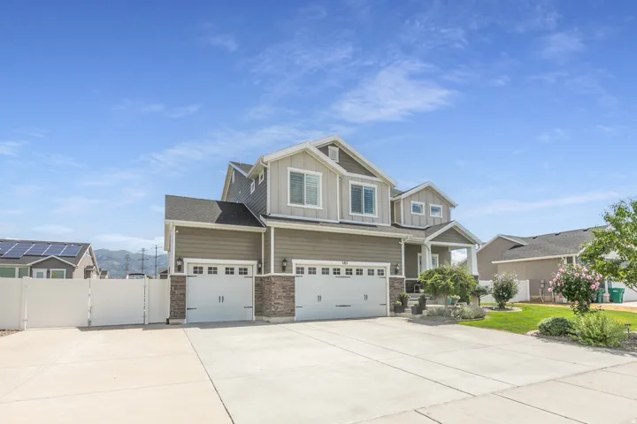 Two-story exterior with a covered porch entry, dual two-car garages with carriage-style doors, and stone accents