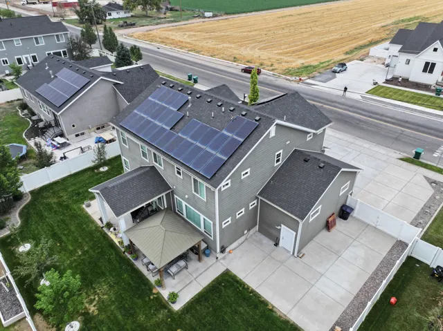 Solar panel array, covered patio, expansive concrete hardscaping, attached garage, white privacy fencing