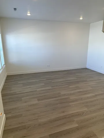 Recessed lighting, wood-finish flooring, white walls, and a window with blinds