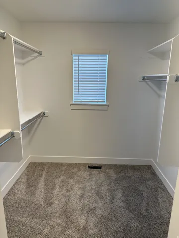 Custom closet system with built-in shelving, hanging rods, and window with horizontal blinds