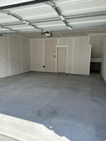 Spacious garage featuring a concrete floor, automatic garage door opener, and interior access door