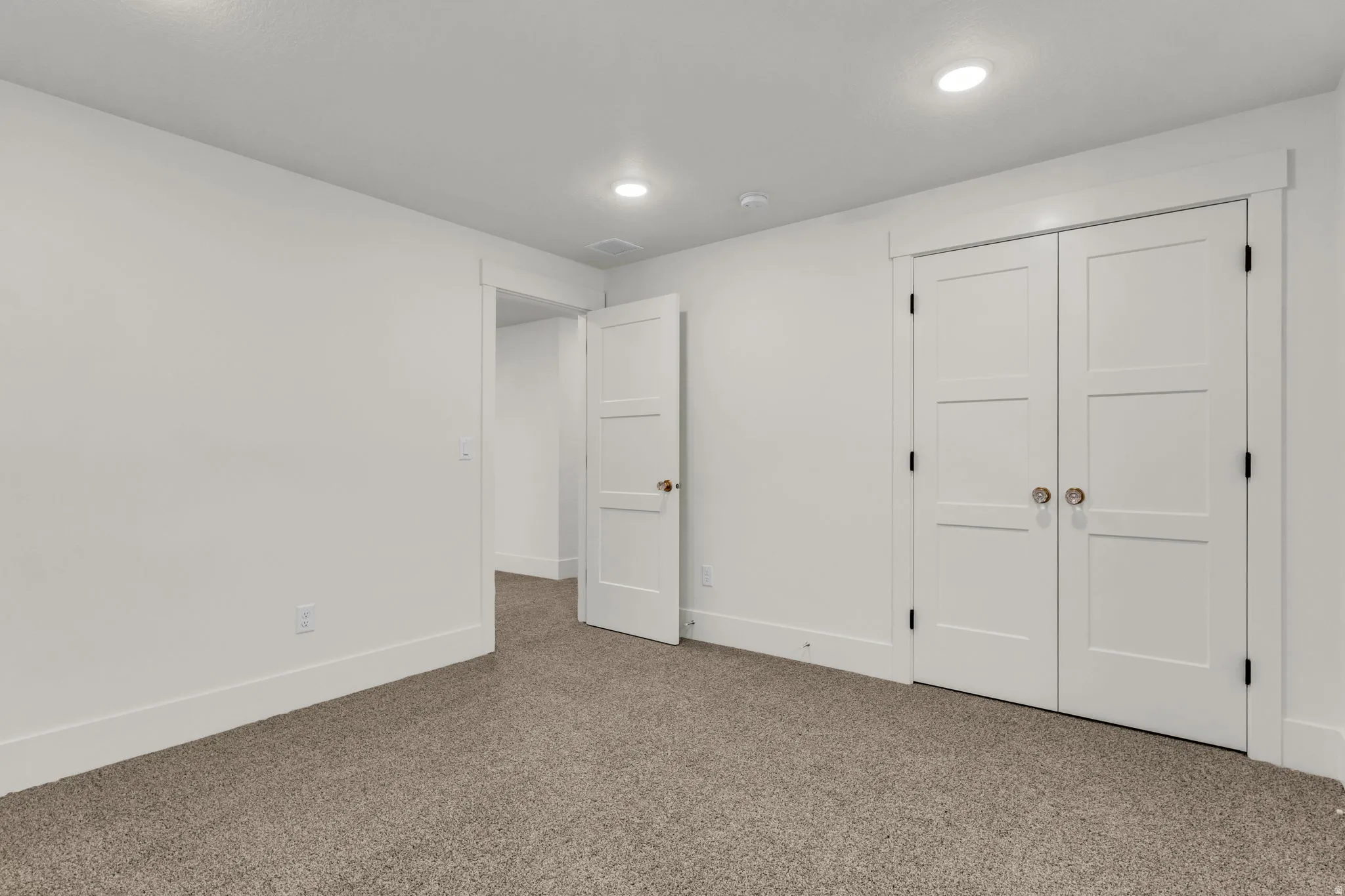 Recessed ceiling lighting, white interior doors, and neutral carpeting
