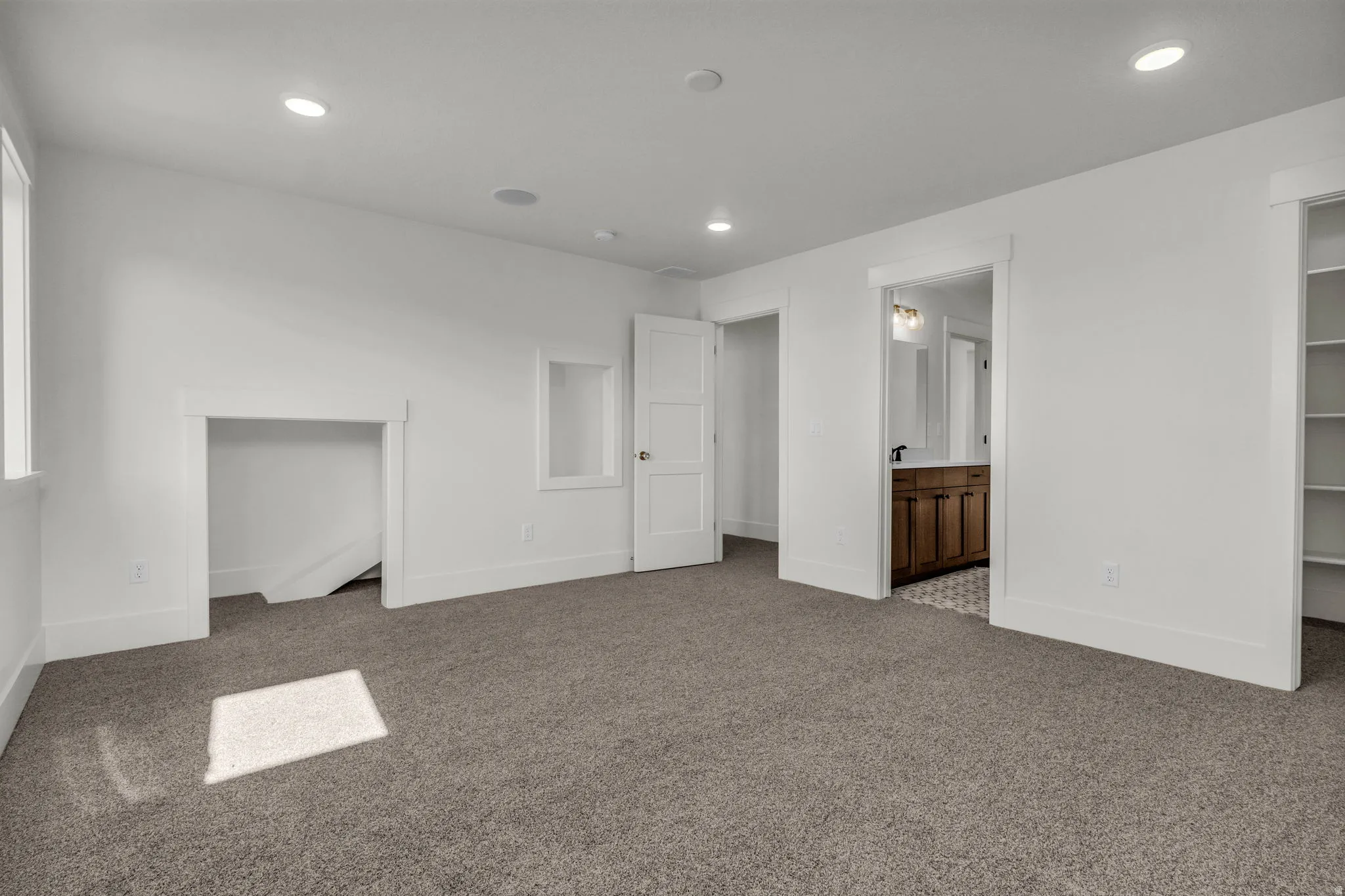 Carpeted flooring with recessed lighting, built-in shelving, and a framed alcove