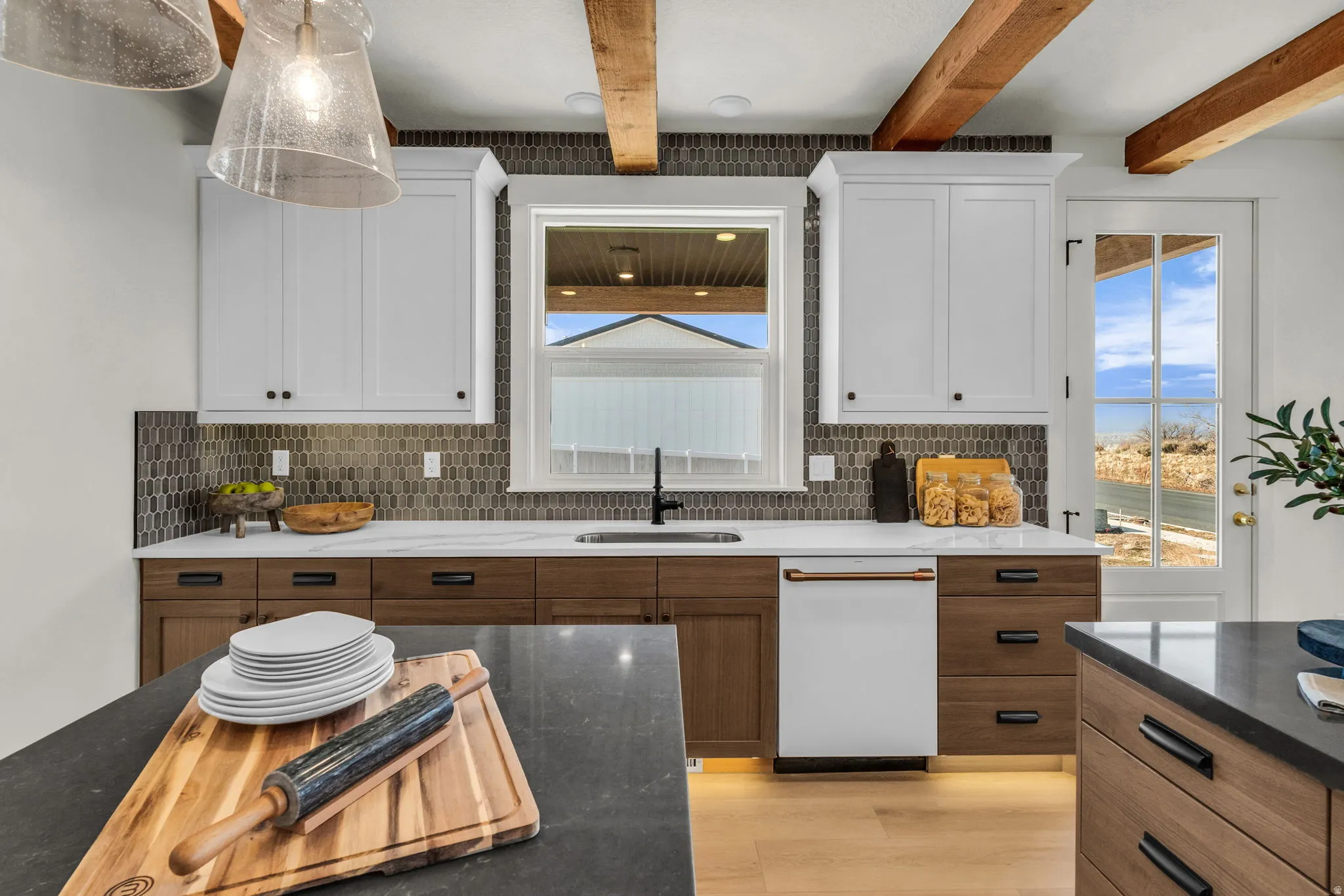 Kitchen featuring exposed wood beams, white upper cabinetry, wood-finish lower cabinetry, a built-in dishwasher, and a patterned tile backsplash