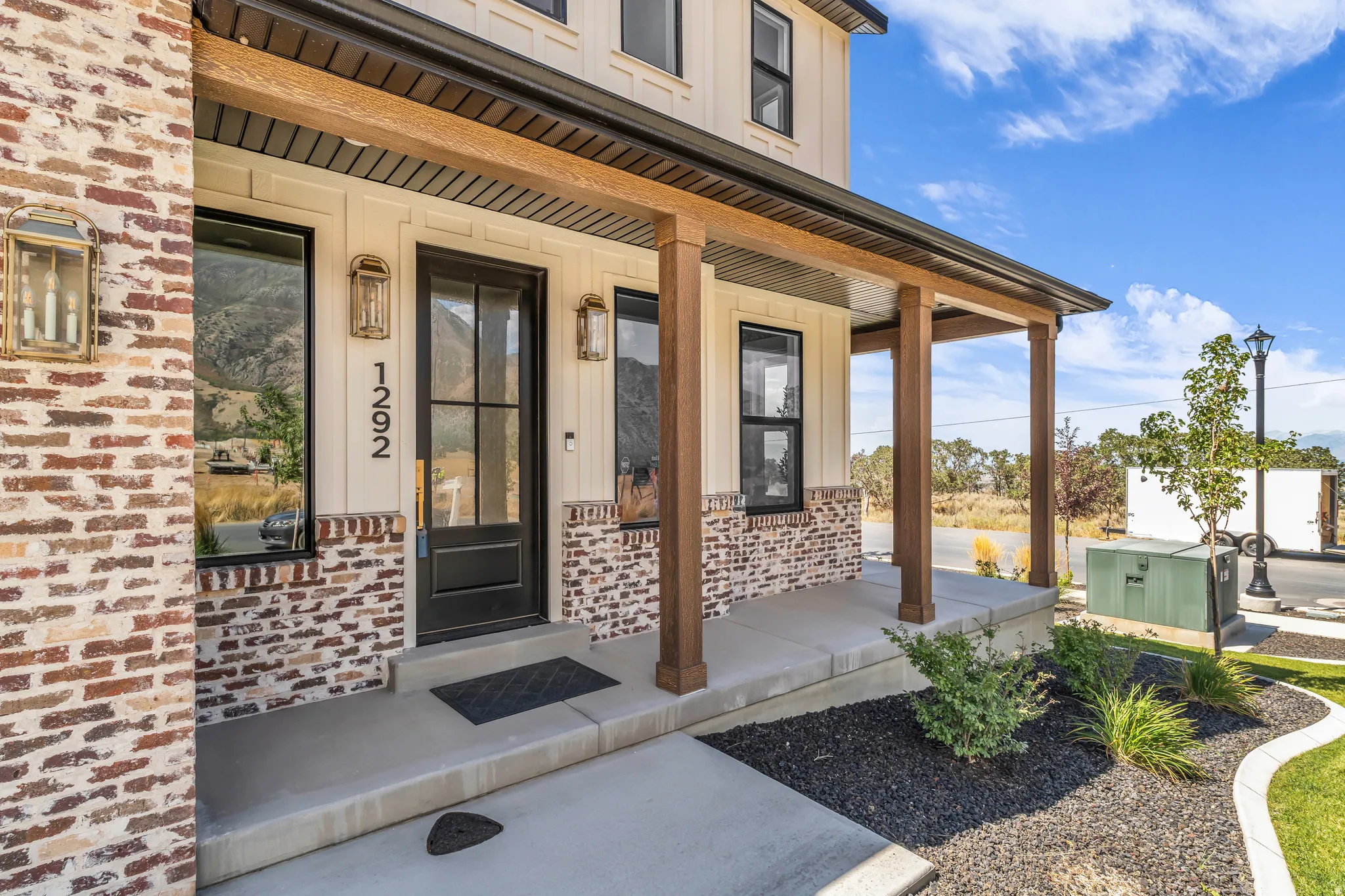 Covered front porch featuring wood-finish columns, brick accents, and board and batten siding