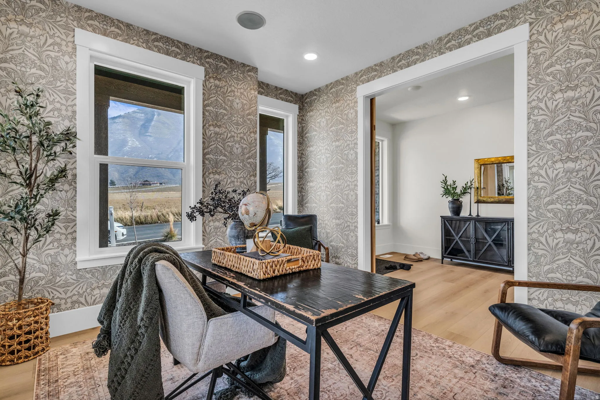 Patterned wallpaper, recessed lighting, wood-finish flooring, white window trim, and a mountain backdrop