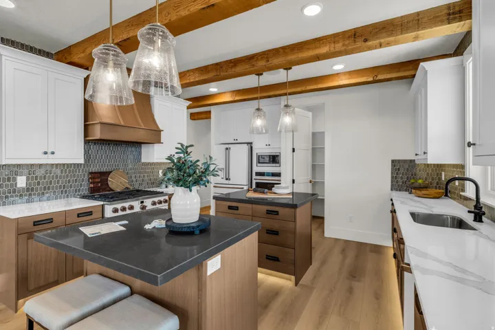 Gourmet kitchen featuring a gas range, custom range hood, wood-finish flooring, two islands, and exposed wood beams