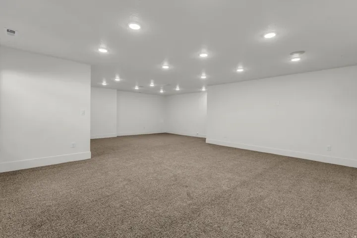Spacious room featuring neutral carpeting, recessed lighting, and crisp white walls