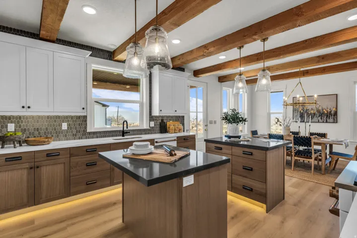 Kitchen featuring exposed ceiling beams, dual kitchen islands with dark countertops, wood-finish flooring, a mosaic tile backsplash, and shaker-style cabinetry